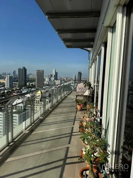 คอนโด ให้เช่าในWatthana, Bangkok - ทางเดินระเบียงยาว มีกระถางต้นไม้ ราวกระจก และวิวเมืองพาโนรามา