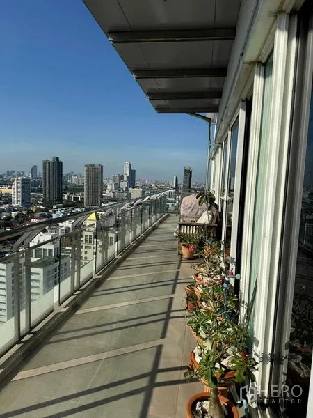 คอนโด ให้เช่าในWatthana, Bangkok - ทางเดินระเบียงยาว มีกระถางต้นไม้ ราวกระจก และวิวเมืองพาโนรามา