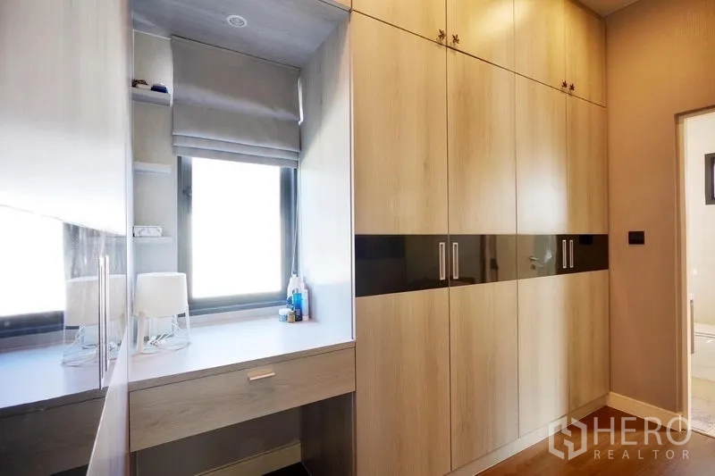独立式住宅 出租或出售在Bang Kapi, Bangkok - 步入式衣帽间走廊，满墙柜体与窗边梳妆台。