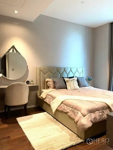 Condominium for rent in Watthana, Bangkok - Cozy bedroom with upholstered bed, dressing table and soft lighting on wood floors.