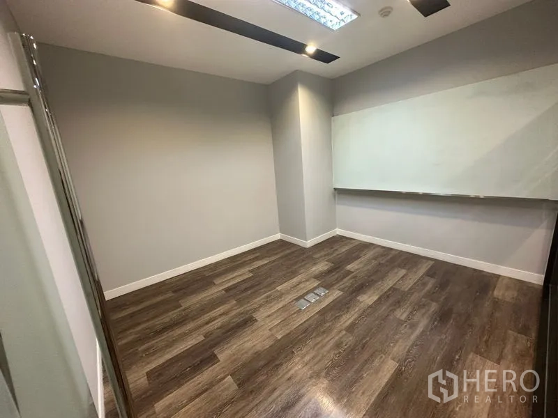 Office Space for rent - Compact meeting or training room with wall-mounted whiteboard, recessed lights and dark wood flooring.