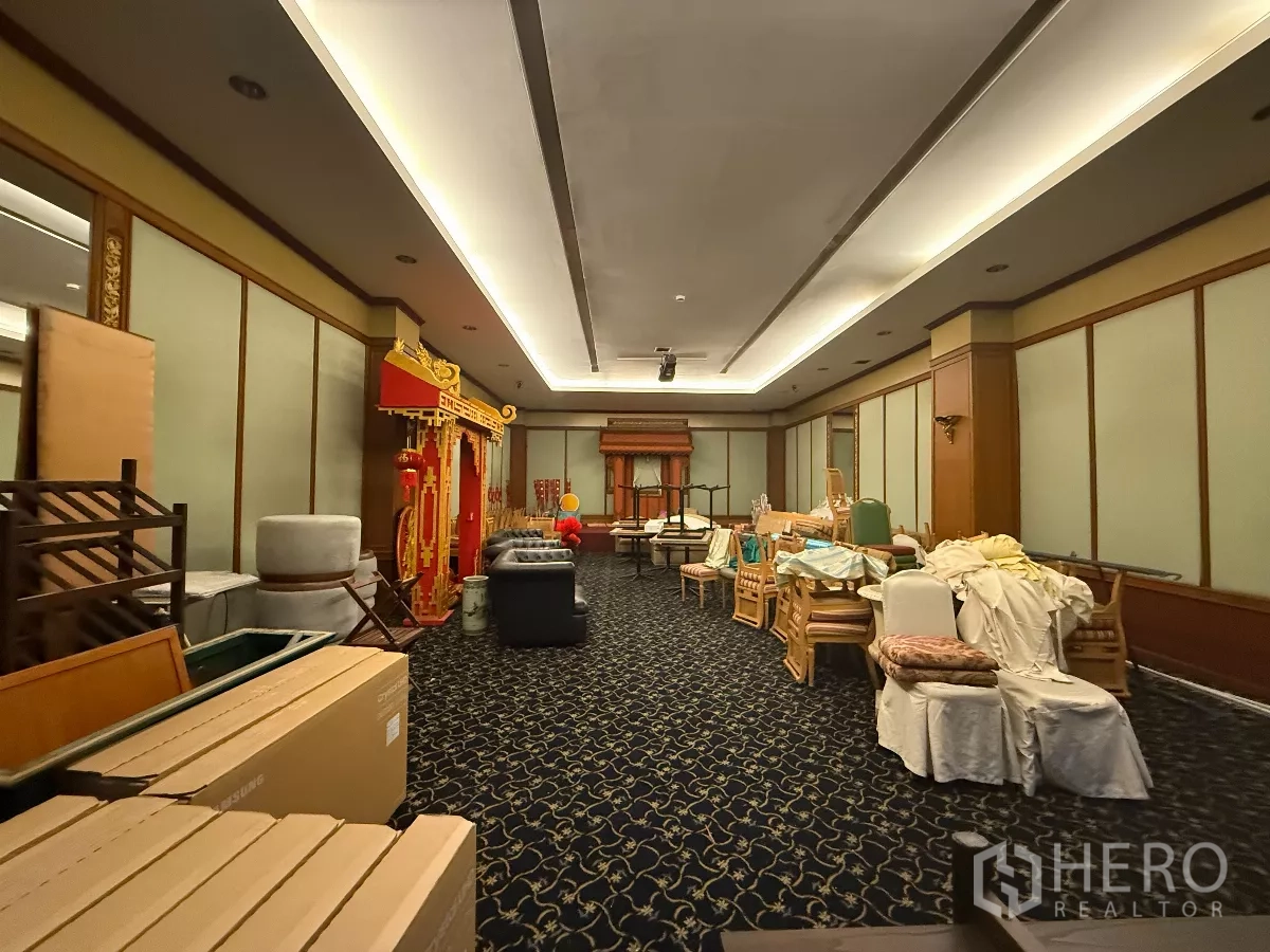 零售空间 出租在Pathum Wan, Bangkok - 大型铺面功能厅，地毯地面、隐藏灯带与木墙板，内有存放家具。