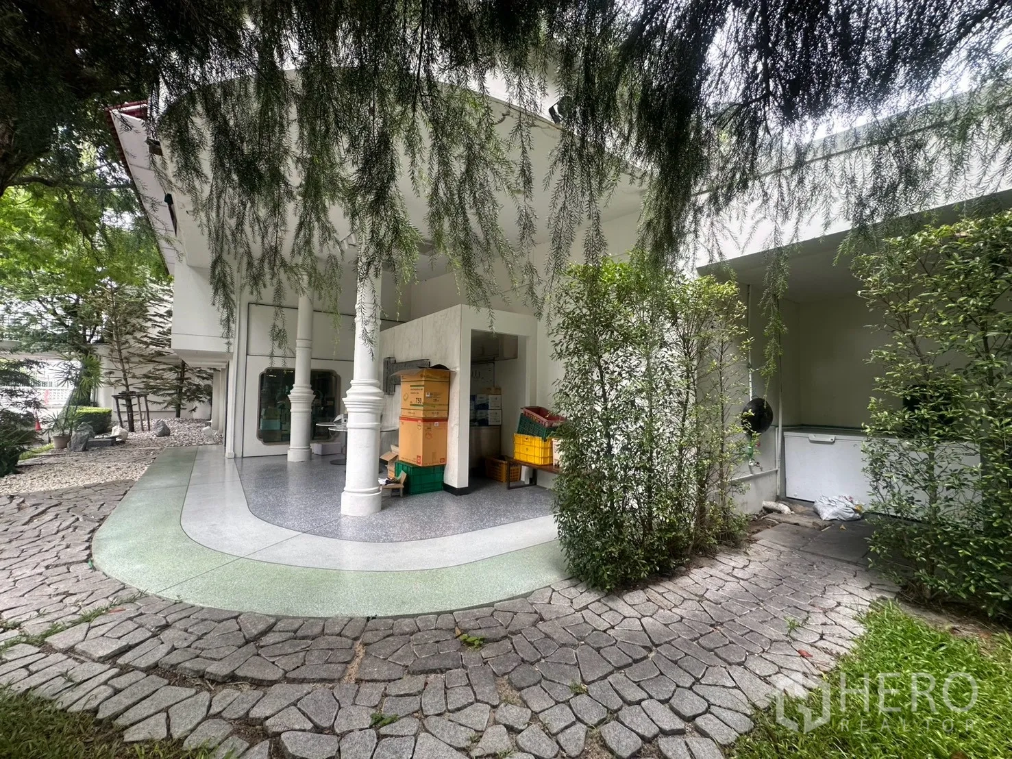 Detached House for rent in Watthana, Bangkok - Side garden with curved patio, stone path, and hanging greenery.