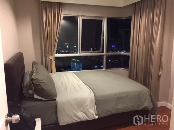Condominium for rent in Huai Khwang, Bangkok - Secondary bedroom with double bed and corner windows offering panoramic views.