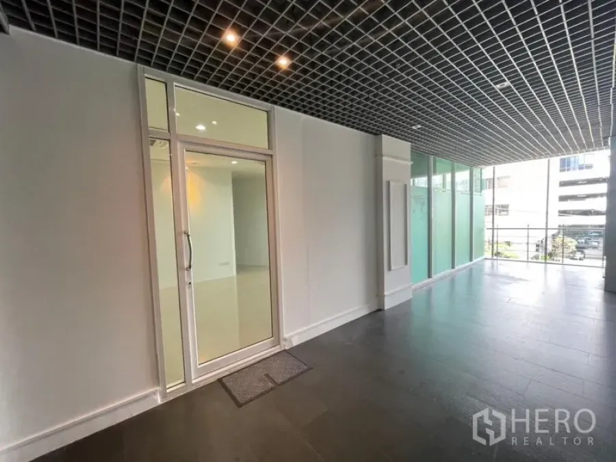 Office Space for rent in Khlong Toei, Bangkok - Semi-outdoor lobby with grid ceiling, frosted glass panels and a glass door entrance to the office.
