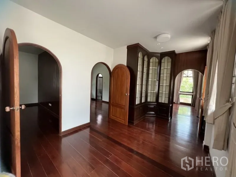 Detached House for rent in Ratchathewi, Bangkok - Spacious upper level with multiple arched doorways, glass cabinet and wood flooring.