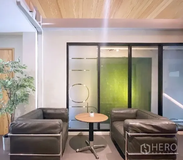 办公空间 出租在Bang Rak, Bangkok - 邦拉区办公室的接待区：黑色皮沙发、圆形茶几与磨砂玻璃隔断