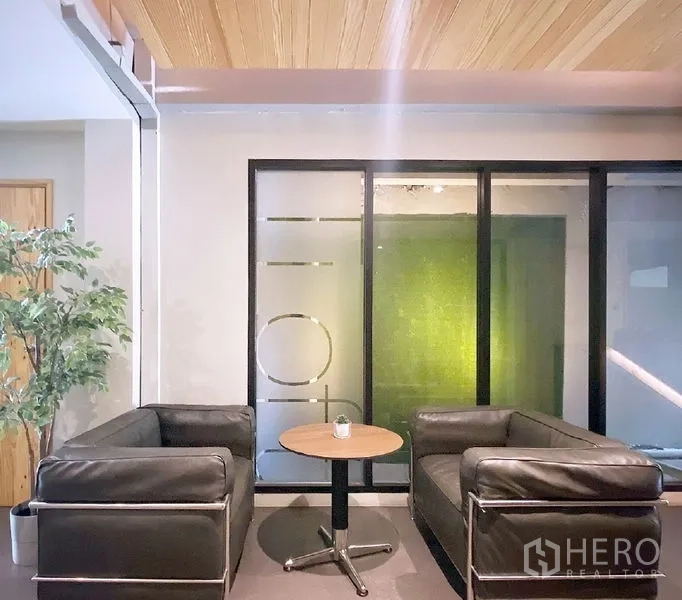 办公空间 出租在Bang Rak, Bangkok - 邦拉区办公室的接待区：黑色皮沙发、圆形茶几与磨砂玻璃隔断