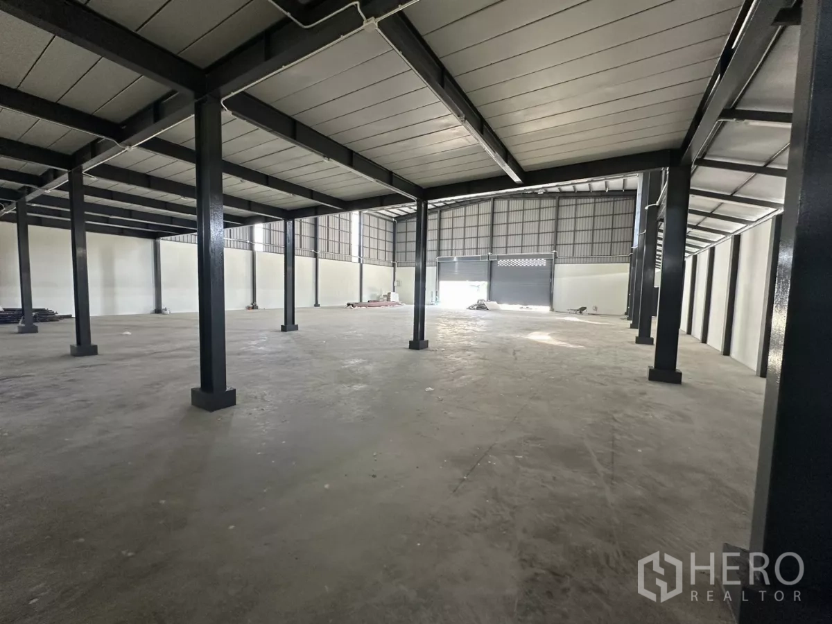 货栈 出租在Prawet, Bangkok - 夹层下的宽阔区域，混凝土地面与结构立柱。
