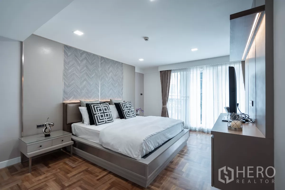 Apartment for rent - Primary bedroom with feature headboard, TV cabinet and sheer curtains.