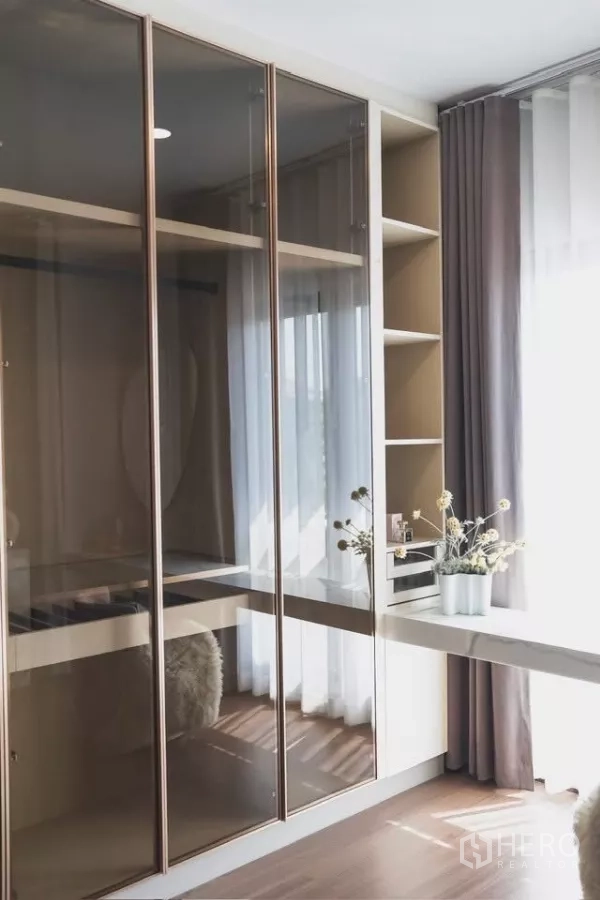 Detached House for rent in Bang Phli, Samut Prakan - Walk-in closet with glass-front wardrobes and shelving beside a window.