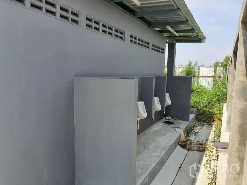 โรงงาน ให้เช่าในMueang Samut Prakan, Samut Prakan - อาคารห้องน้ำชายภายนอก มีโถปัสสาวะใต้หลังคาข้างลานโรงงาน