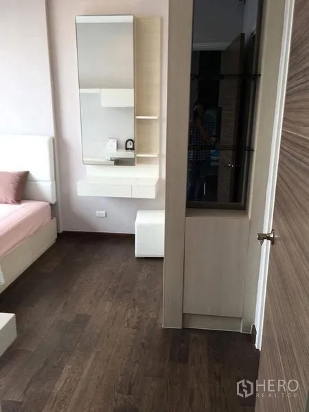 Condominium for rent in Ratchathewi, Bangkok - Entrance to bedroom with vanity and built-in storage over dark wood flooring.