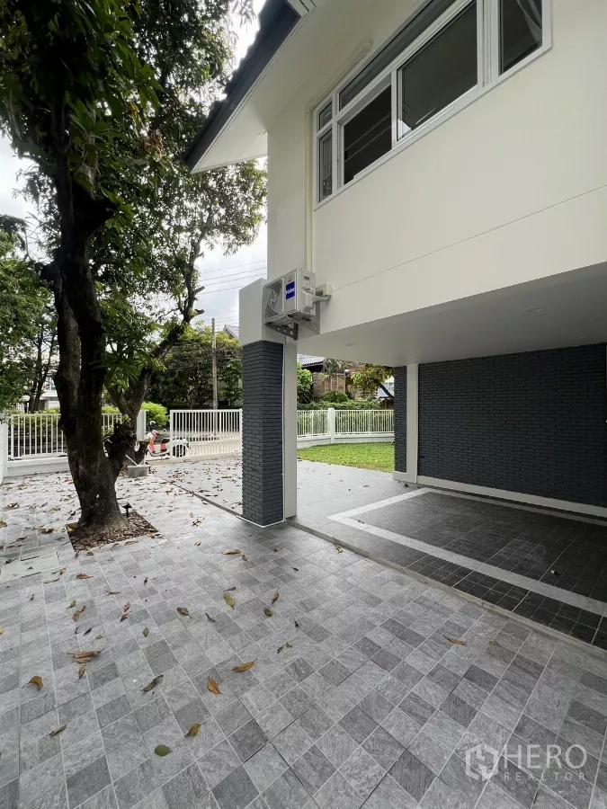 Detached House for rent in Saphan Sung, Bangkok - Covered carport with gray brick pillars and view to lawn and street fence.