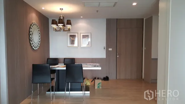Condominium for rent in Khlong Toei, Bangkok - Dining area with four-seat table, chandelier lighting and wood-paneled feature wall.