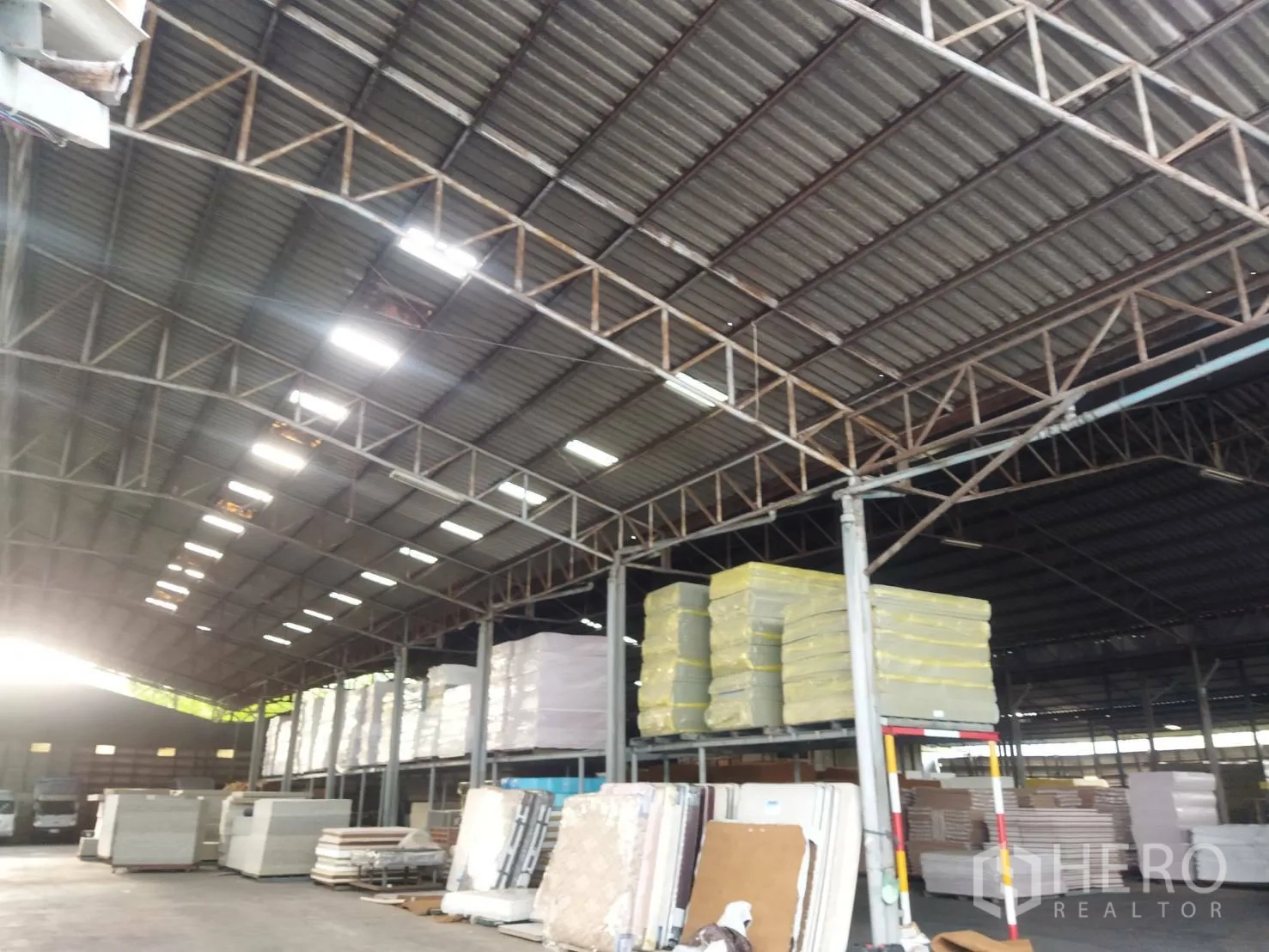Warehouse for rent in Bang Khun Thian, Bangkok - Interior storage zone with stacked materials and open bays under a wide clear-span roof.
