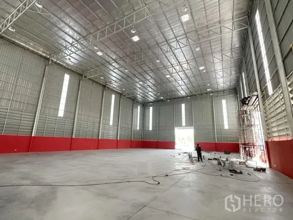 Warehouse for rent in Khlong Luang, Pathum Thani - Open clear-span warehouse hall with insulated metal roof, tall vertical light panels and smooth concrete floor.