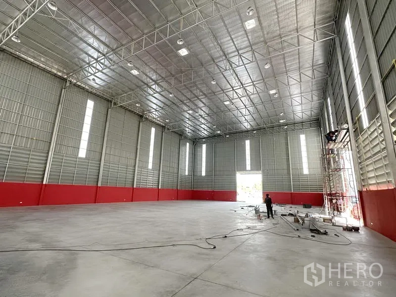 Warehouse for rent in Khlong Luang, Pathum Thani - Open clear-span warehouse hall with insulated metal roof, tall vertical light panels and smooth concrete floor.