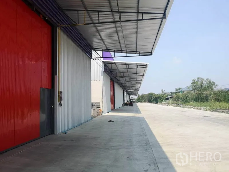 货栈 出租在Sai Mai, Bangkok - 带雨棚的装卸走道，红色仓门与宽阔车道，适合卡车通行