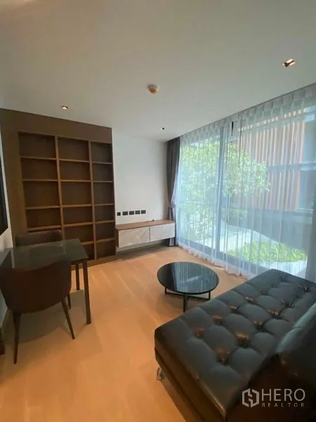 公寓 出租在Watthana, Bangkok - 采光充足的客厅，落地窗、嵌入式书架与书桌，欣赏花园景