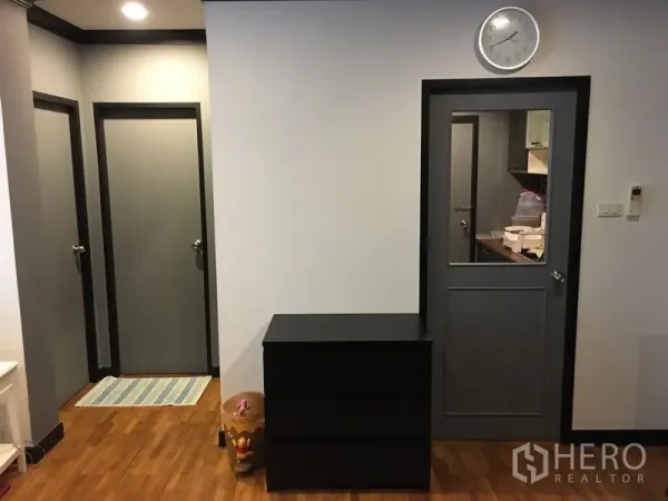 公寓 出售在Khlong Toei, Bangkok - 走廊设多扇门与墙钟，木地板通往卧室与厨房。