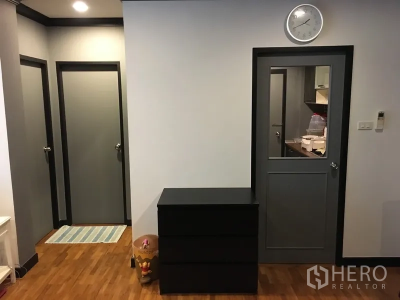 公寓 出售在Khlong Toei, Bangkok - 走廊设多扇门与墙钟，木地板通往卧室与厨房。