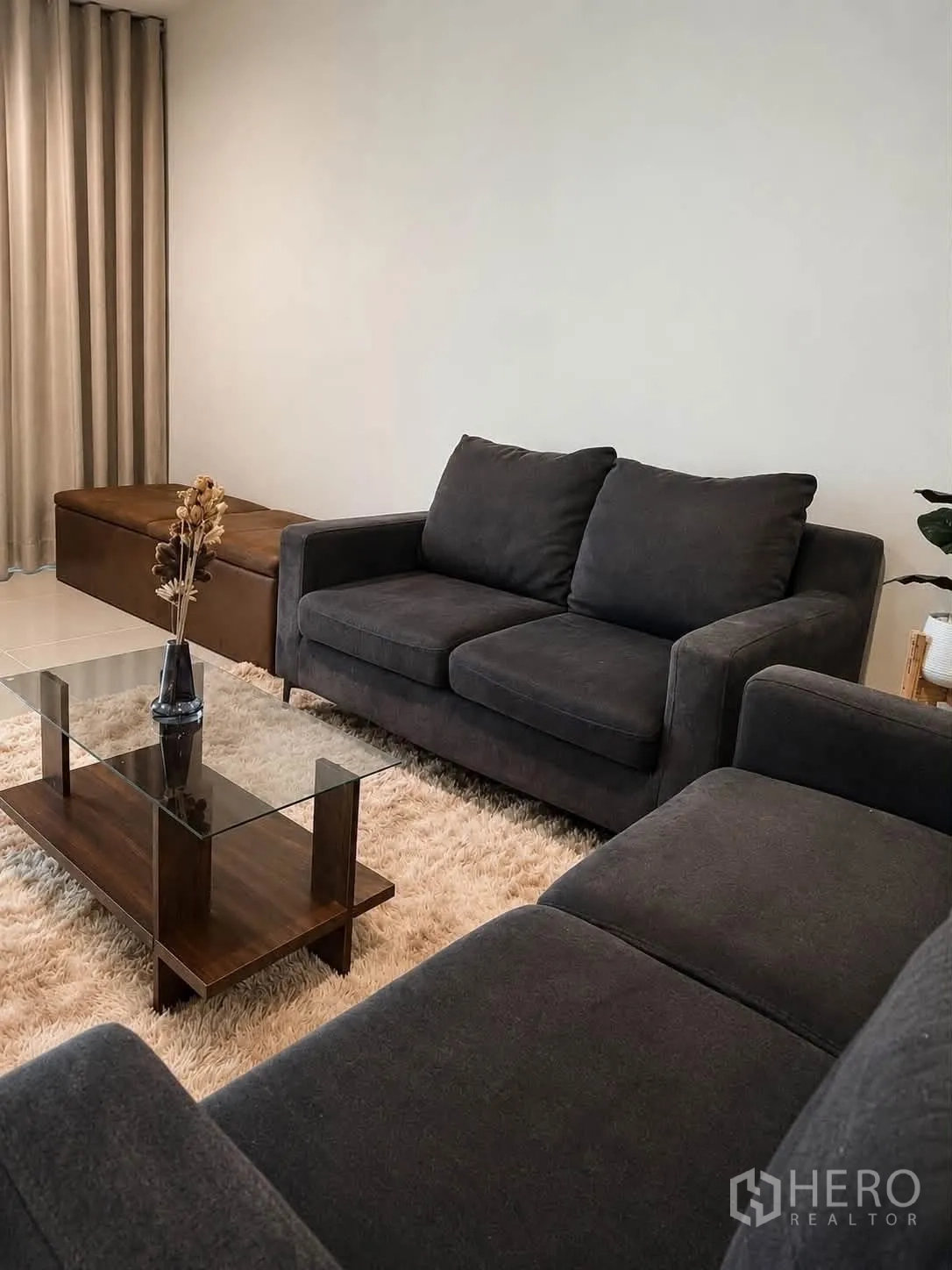Townhouse for rent in Bang Phli, Samut Prakan - Living room with dark sofas, a glass coffee table, and a shaggy rug.