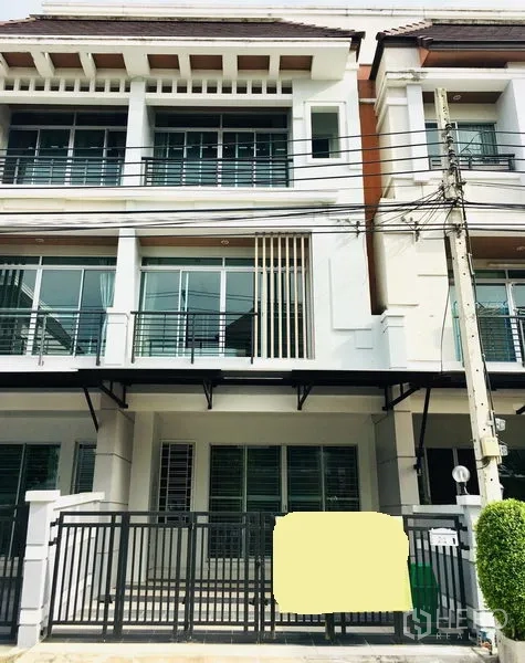 联排别墅 出租在Prawet, Bangkok - 曼谷Prawet区三层联排别墅外观，带阳台与前院大门停车位。