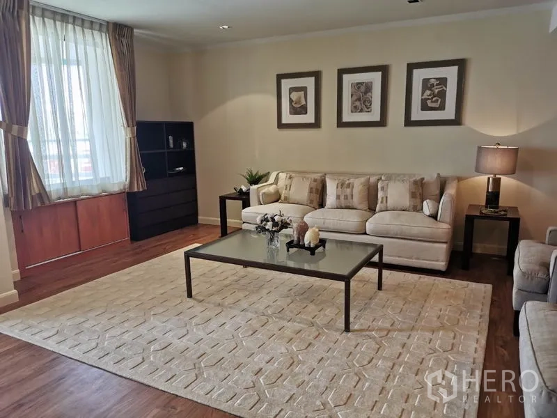 Condominium for rent in Watthana, Bangkok - Bright living room with beige sofas, glass coffee table, large rug and hardwood floors.