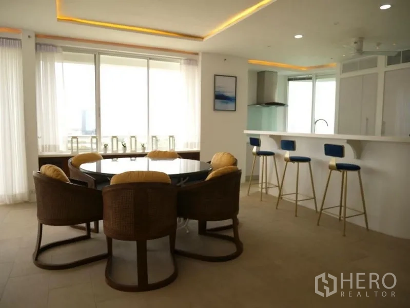 คอนโด ให้เช่าในKhlong Toei, Bangkok - โต๊ะอาหารทรงกลมและเคาน์เตอร์บาร์พร้อมสตูลสีน้ำเงินข้างหน้าต่างบานใหญ่