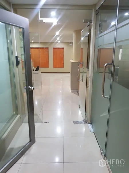 Office Space for rent - Glass-door corridor leading into a bright tiled office reception area.