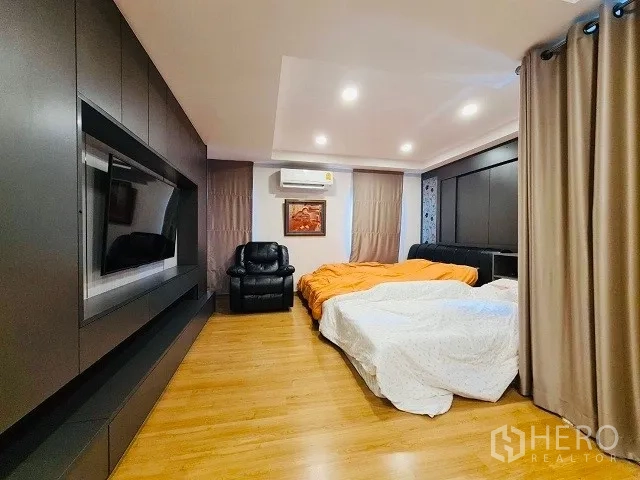 Detached House for sale in Suan Luang, Bangkok - Spacious bedroom with wood flooring, built‑in cabinetry, air‑conditioning, and soft lighting.