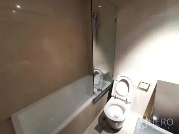 คอนโด ให้เช่าหรือขายในSathon, Bangkok - ห้องน้ำสมัยใหม่พร้อมอ่างอาบน้ำ ฉากกั้นกระจก และโถสุขภัณฑ์ โทนสีอบอุ่น