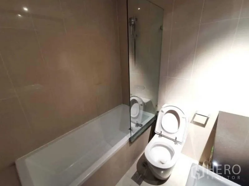 คอนโด ให้เช่าหรือขายในSathon, Bangkok - ห้องน้ำสมัยใหม่พร้อมอ่างอาบน้ำ ฉากกั้นกระจก และโถสุขภัณฑ์ โทนสีอบอุ่น