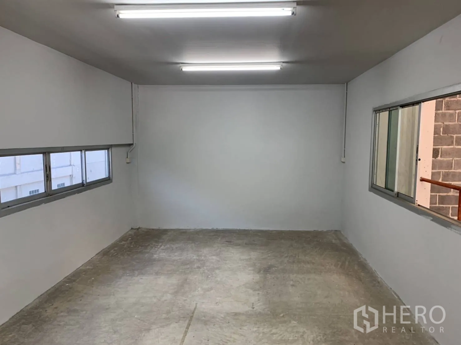 Warehouse for rent in Khlong Sam Wa, Bangkok - Long upper-level office with windows and concrete flooring.