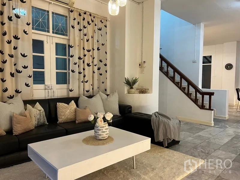 Home Office for rent in Suan Luang, Bangkok - Living room with black leather sofa, coffee table and staircase access.