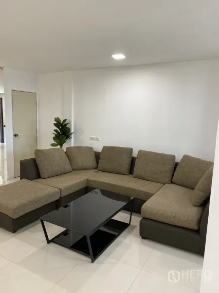 ทาวน์เฮาส์ ให้เช่าในKhlong Toei, Bangkok - ห้องนั่งเล่นกว้าง โซฟาเข้ามุม และโต๊ะกลางกระจกสีดำ