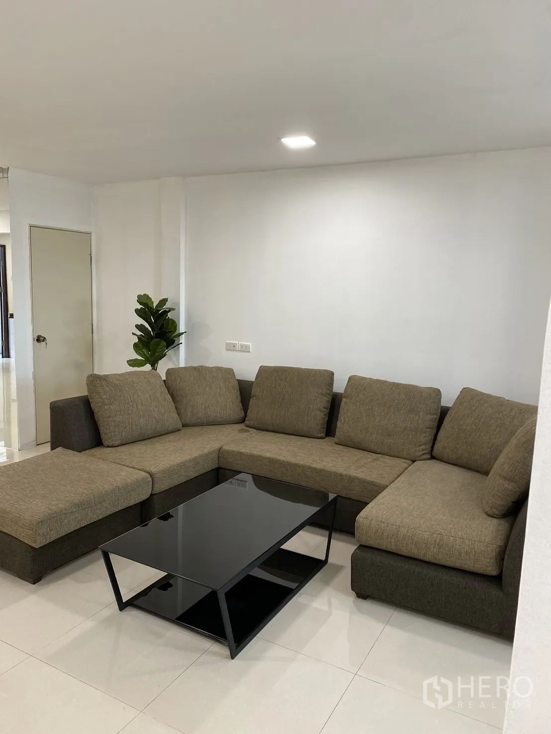 ทาวน์เฮาส์ ให้เช่าในKhlong Toei, Bangkok - ห้องนั่งเล่นกว้าง โซฟาเข้ามุม และโต๊ะกลางกระจกสีดำ