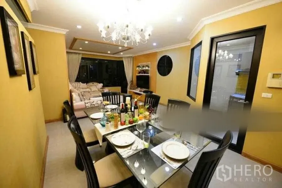 Condominium for rent in Bang Kho Laem, Bangkok - Bright dining area with a glass-top table and chandelier opening to a cozy living room.