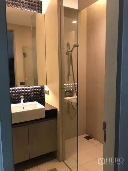 Townhouse for rent in Khlong Toei, Bangkok - Compact bathroom with vanity, mirror and a glass-enclosed shower.