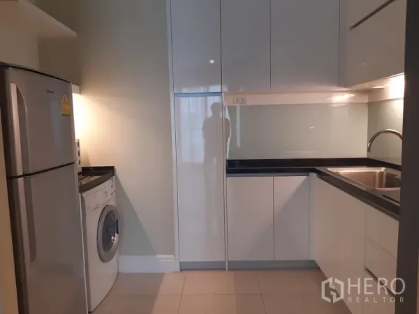 คอนโด ให้เช่าหรือขายในKhlong Toei, Bangkok - ครัวรูปตัว U ตู้ไฮกลอสสีขาว ซิงก์ ตู้เย็น และเครื่องซักผ้า