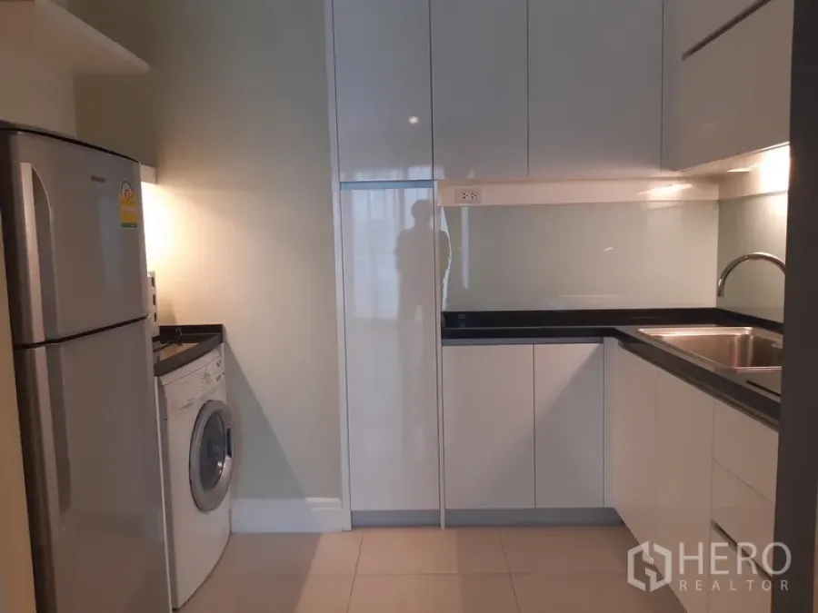 公寓 出租或出售在Khlong Toei, Bangkok - 现代U型厨房，白色亮面橱柜，水槽、冰箱与滚筒洗衣机