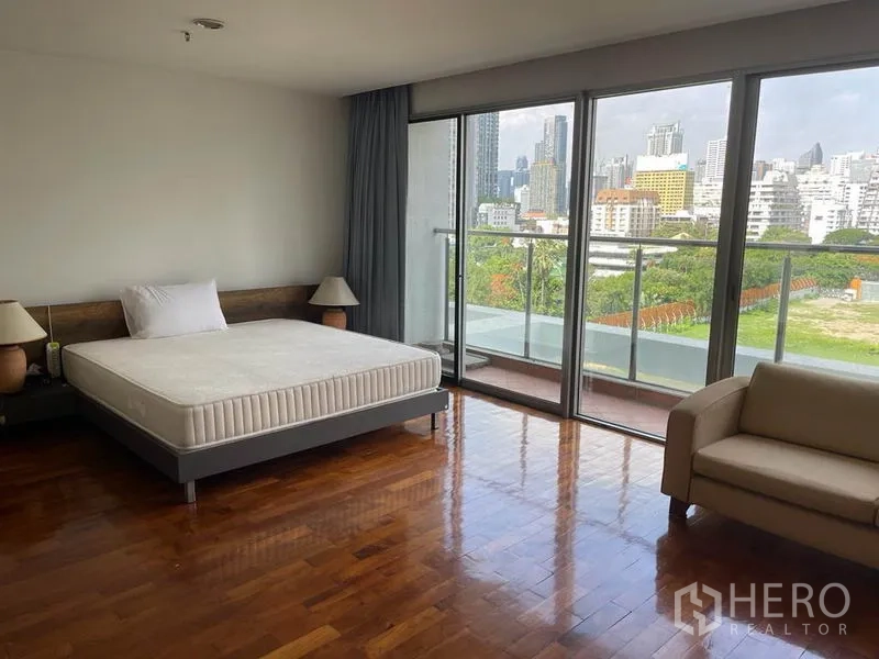 公寓 出租在Pathum Wan, Bangkok - 主卧铺木地板，透过大阳台窗可欣赏城市全景。
