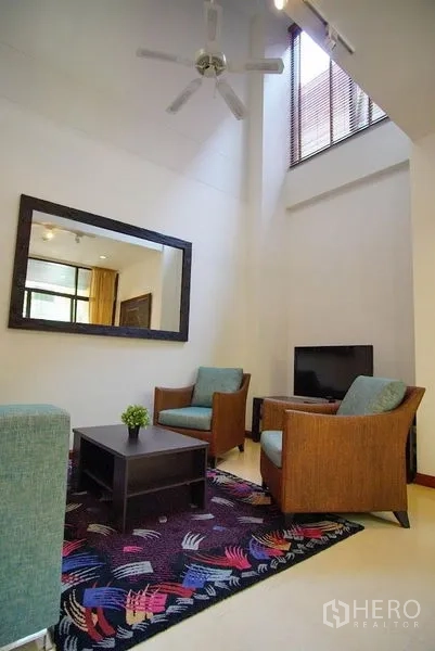 Townhouse for rent in Watthana, Bangkok - Double-height living room with ceiling fan and high window for natural light.