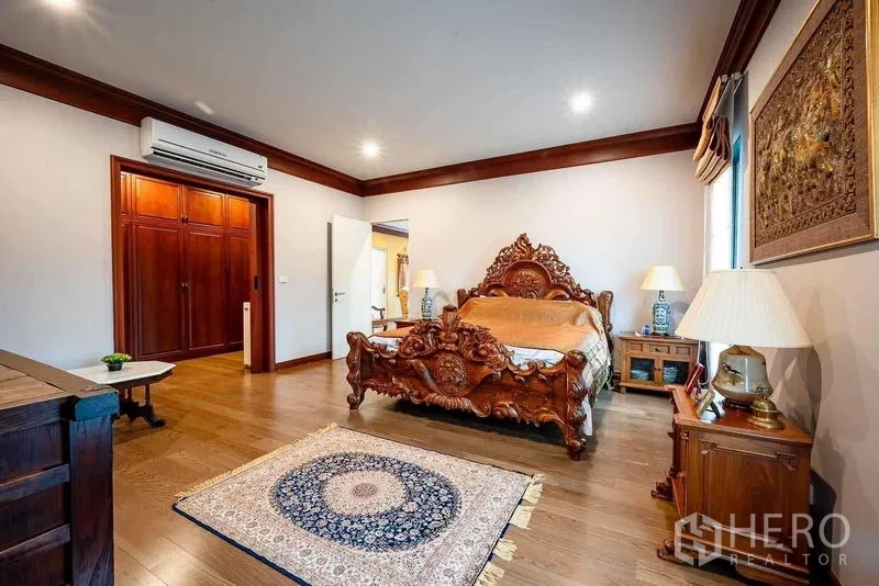 Detached House for sale in Prawet, Bangkok - Spacious master bedroom with ornate carved wooden bed and wood floors.