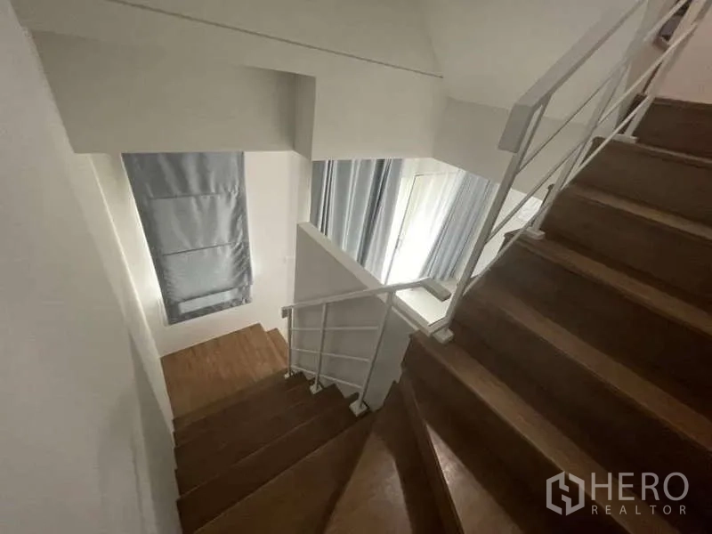 Townhouse for rent or sale in Phasi Charoen, Bangkok - Wooden staircase with white metal railing and natural light.