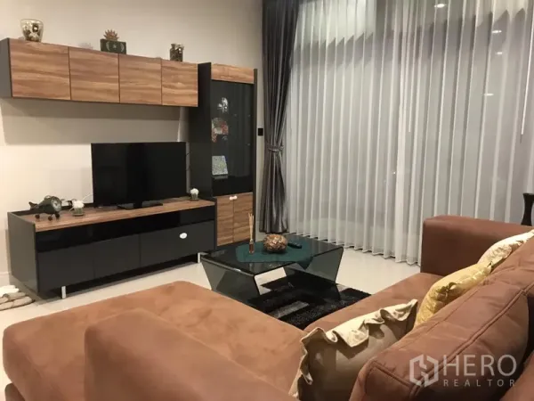 Detached House for rent in Bang Kapi, Bangkok - Living room with media wall, wood-and-black cabinets, glass coffee table and full-height curtains.