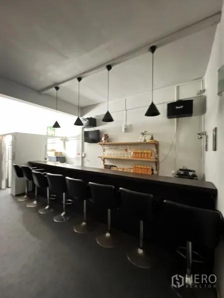 店屋 出租在Khlong Toei, Bangkok - 明亮吧台区，成排吧椅、锥形吊灯与玻璃杯置物架。