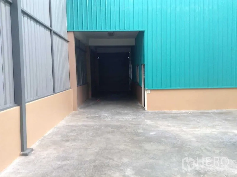 Warehouse for rent in Bang Phli, Samut Prakan - Covered drive-through loading bay beneath teal metal cladding leading into the warehouse.