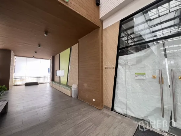 พื้นที่ขายปลีก ให้เช่าในKhlong Toei, Bangkok - พื้นที่ส่วนกลางหน้าร้านมีผนังลายไม้ ม้านั่ง พื้นกระเบื้อง และประตูกระจก.